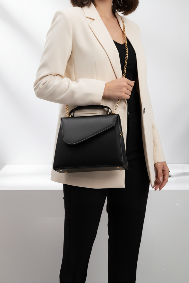 Person holding a black handbag against a white background